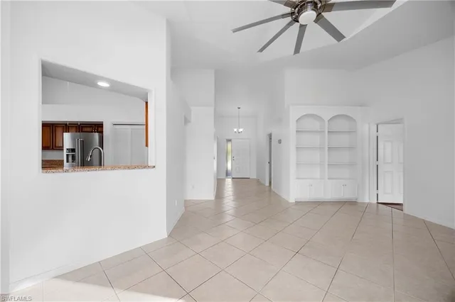 a view of an empty room and window with a chandelier fan