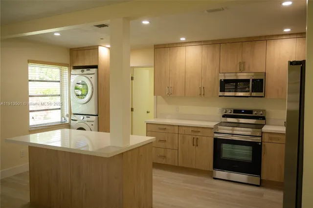 a kitchen with kitchen island a sink stainless steel appliances and cabinets