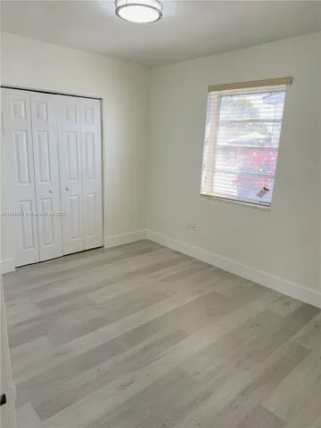 an empty room with wooden floor closet and windows