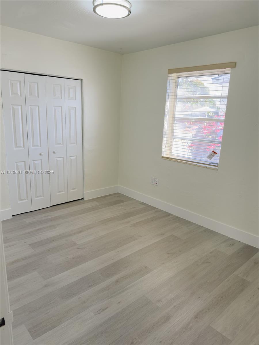 467 Southeast 3rd Street, Unit 1 Hialeah, FL 33010 - Photo 13 of 17 an empty room with wooden floor closet and windows