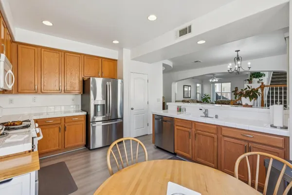 a kitchen with stainless steel appliances granite countertop a refrigerator a sink dishwasher a stove with wooden cabinets and floor