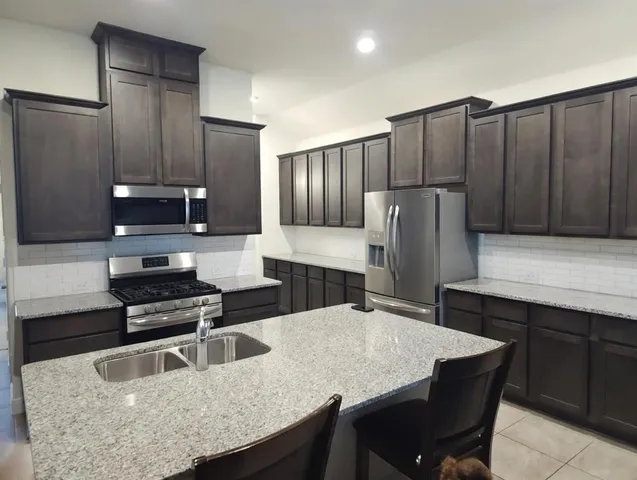 a kitchen with granite countertop a refrigerator and a stove top oven