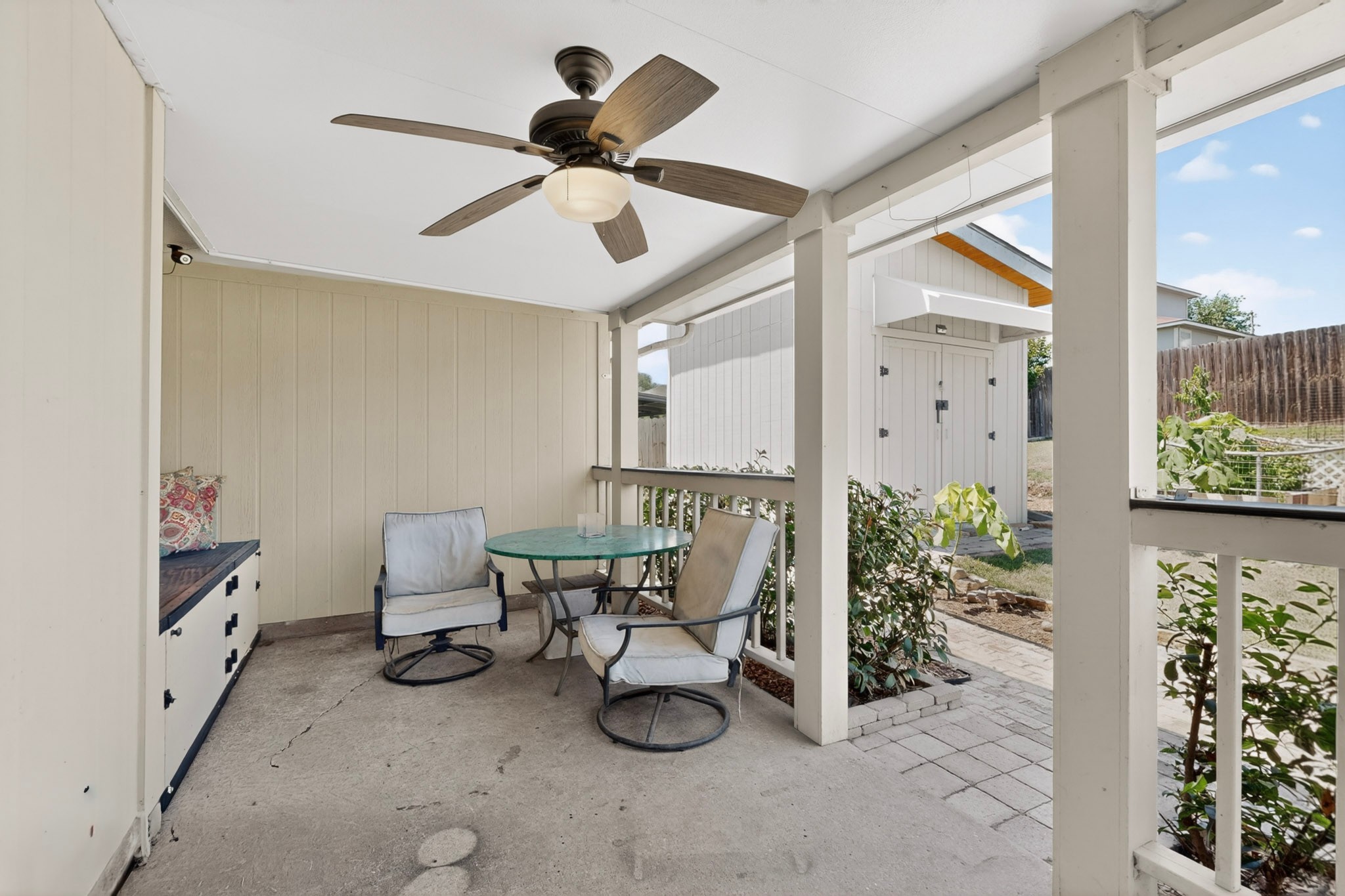 15104 Mimebark Way Austin, TX 78724 - Photo 32 of 38 Covered outdoor patio featuring a ceiling fan with integrated lighting, concrete flooring, and a built-in storage bench with dark hardware
