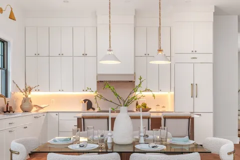 a living room with white couches and kitchen view with wooden floor