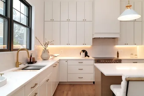 a kitchen with a sink dishwasher and white cabinets with wooden floor
