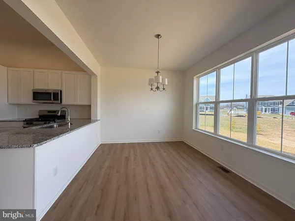 a kitchen with granite countertop a stove a sink and white cabinets with wooden floor