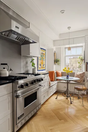 a kitchen with stainless steel appliances a stove a sink dishwasher and white cabinets with wooden floor