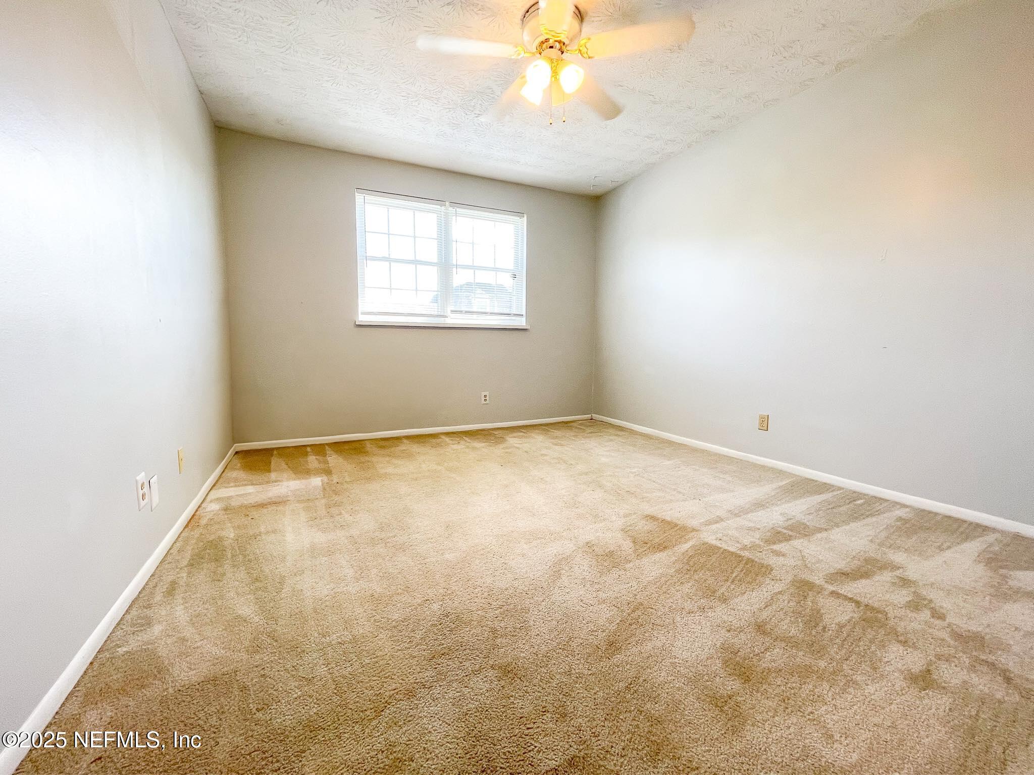 4915 Baymeadows Road, Unit 13D Jacksonville, FL 32217 - Photo 12 of 23 an empty room with a chandelier fan and windows