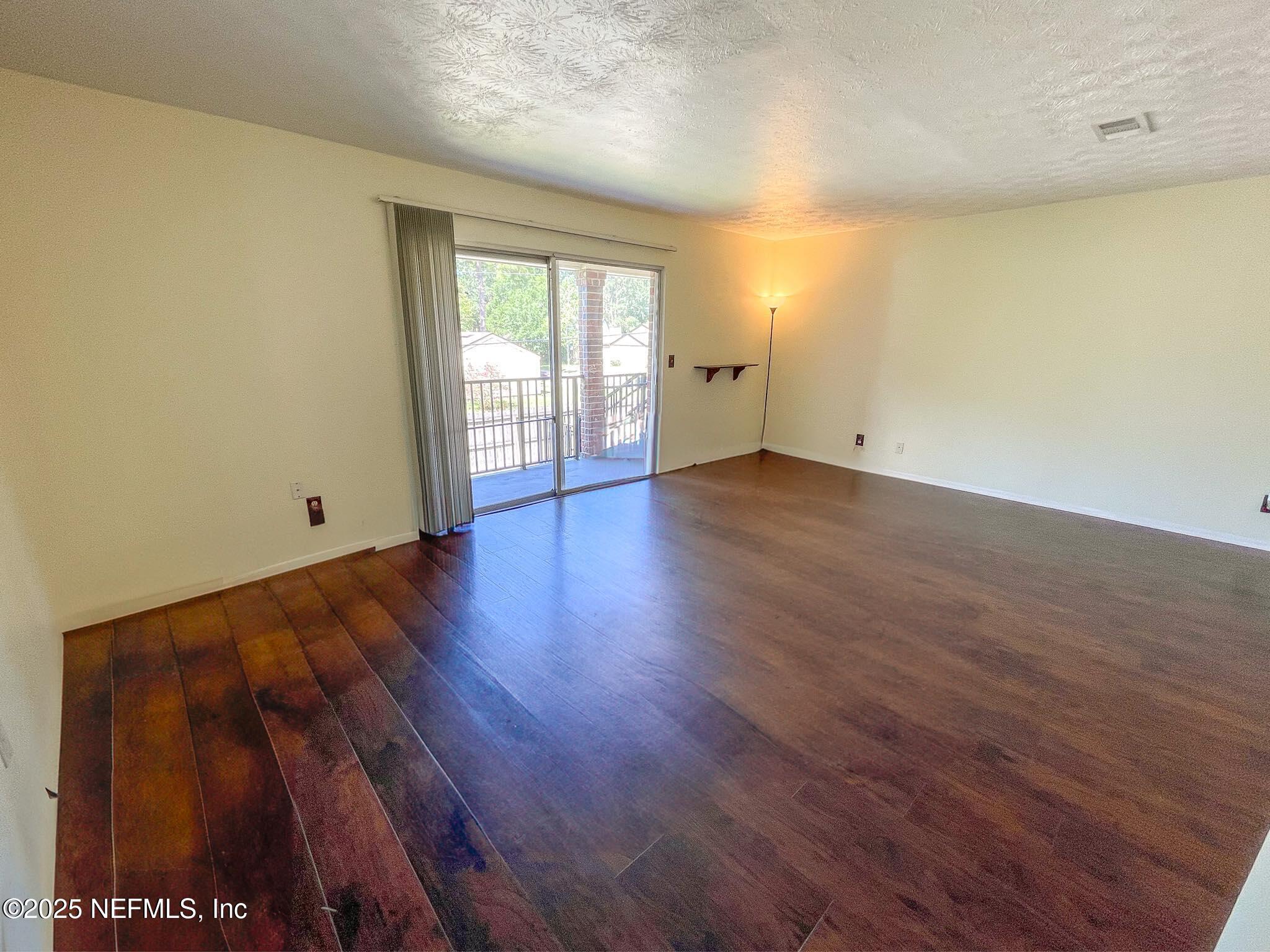 4915 Baymeadows Road, Unit 13D Jacksonville, FL 32217 - Photo 5 of 23 a view of an empty room with wooden floor and a window