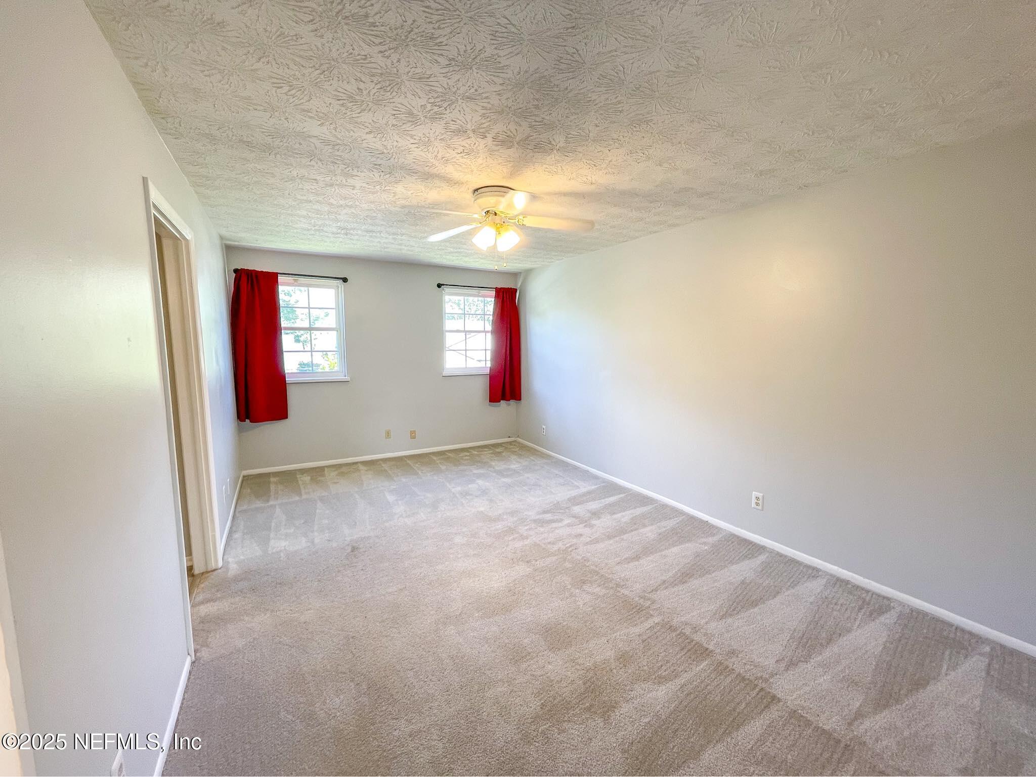 4915 Baymeadows Road, Unit 13D Jacksonville, FL 32217 - Photo 8 of 23 an empty room with windows and fan