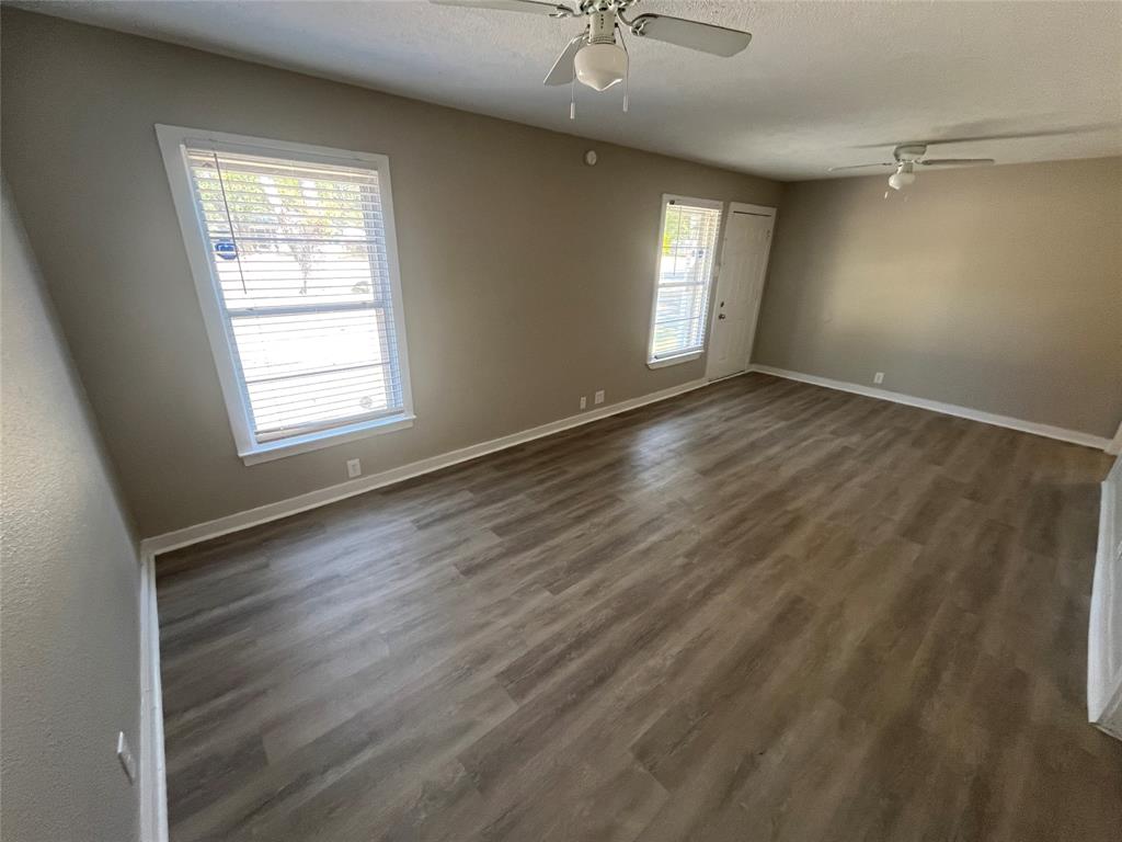 1622 Centerville Road Dallas, TX 75228 - Photo 7 of 19 Spacious room featuring wood-finish flooring, neutral-toned walls, multiple windows with blinds, and two ceiling fans
