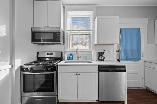 a kitchen with cabinets stainless steel appliances and wooden floor