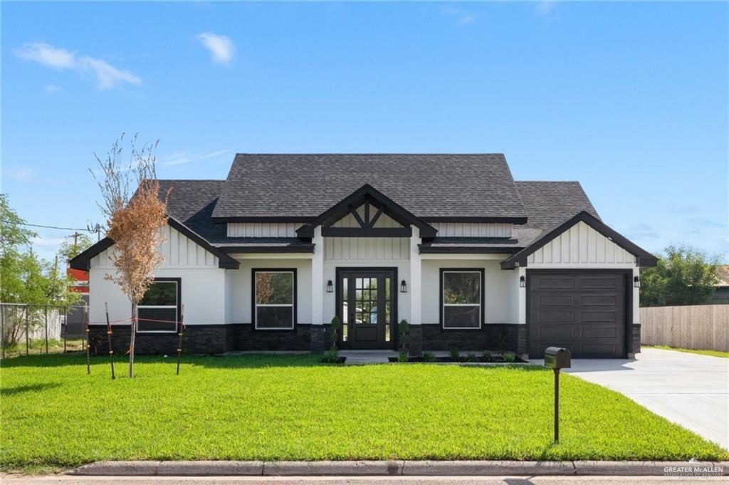 Modern farmhouse style home featuring a shingled roof, board and batten siding, driveway, and an attached garage