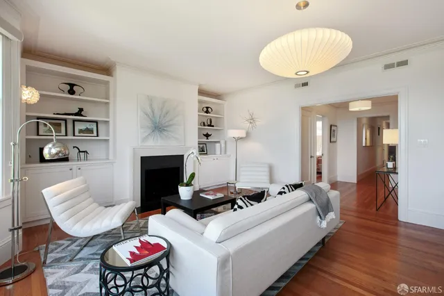 a view of an empty room with wooden floor and a fireplace