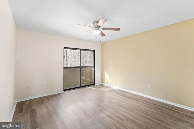 an empty room with wooden floor fan and windows