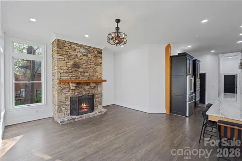a view of an empty room with wooden floor a fireplace and a window