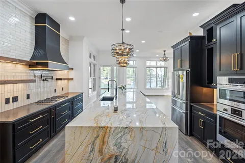 a kitchen with stainless steel appliances granite countertop a refrigerator a sink a stove and a refrigerator