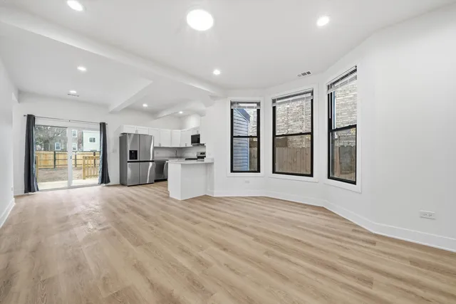 a view of an empty room with window and wooden floor