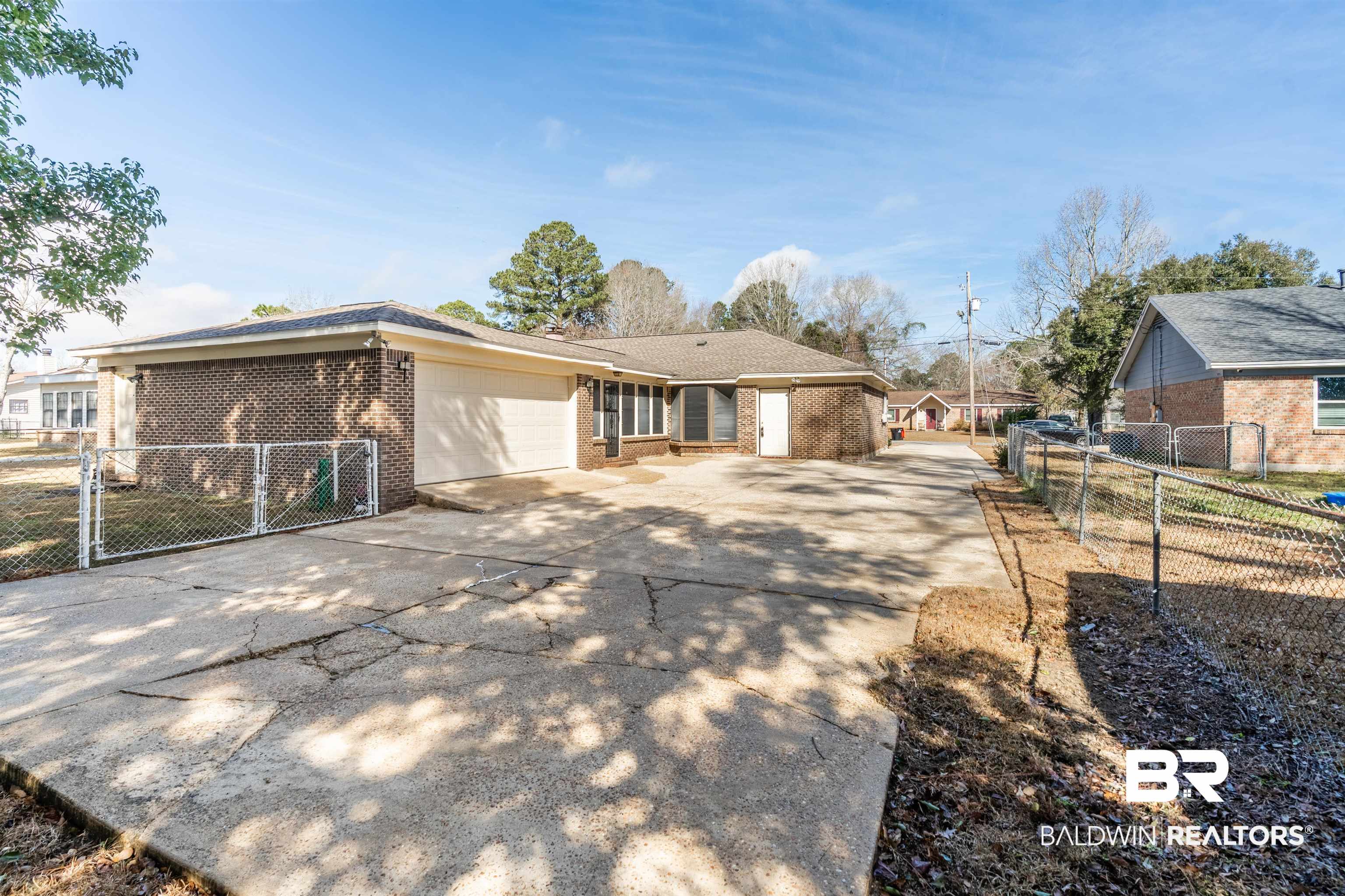 9751 Pine Knoll Road Mobile, AL 36608 - Photo 33 of 36 Back of house featuring a gate, concrete driveway, brick siding, and an attached garage