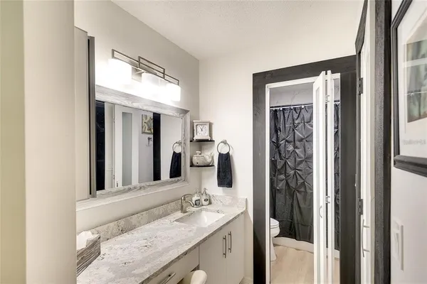 a bathroom with a granite countertop sink vanity mirror and shower