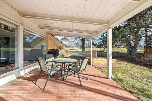 a view of a patio with table and chairs next to yard