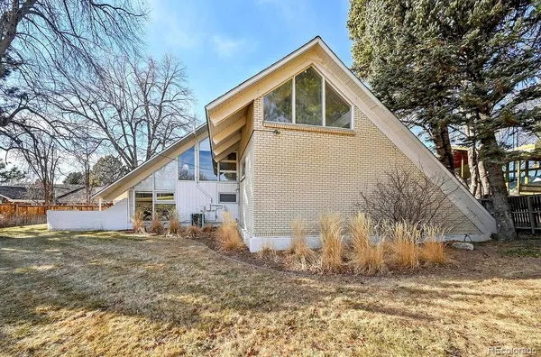 a backyard of a house with large trees and plants