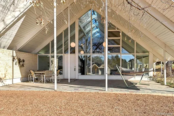 a backyard of a house with large trees and outdoor seating