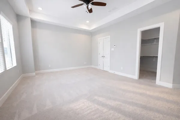 an empty room with view of ceiling fan and window