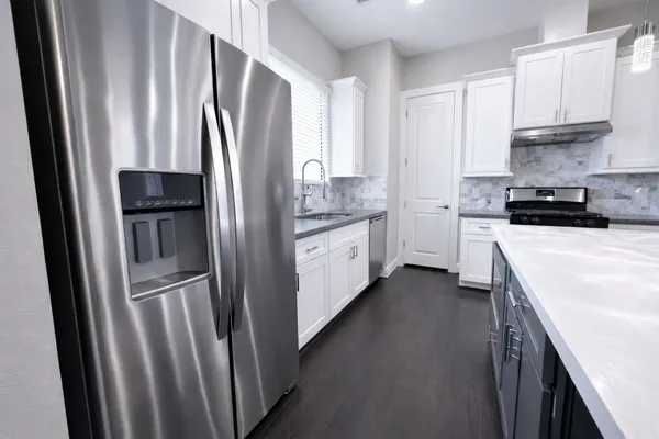 a kitchen with stainless steel appliances a refrigerator sink and white cabinets