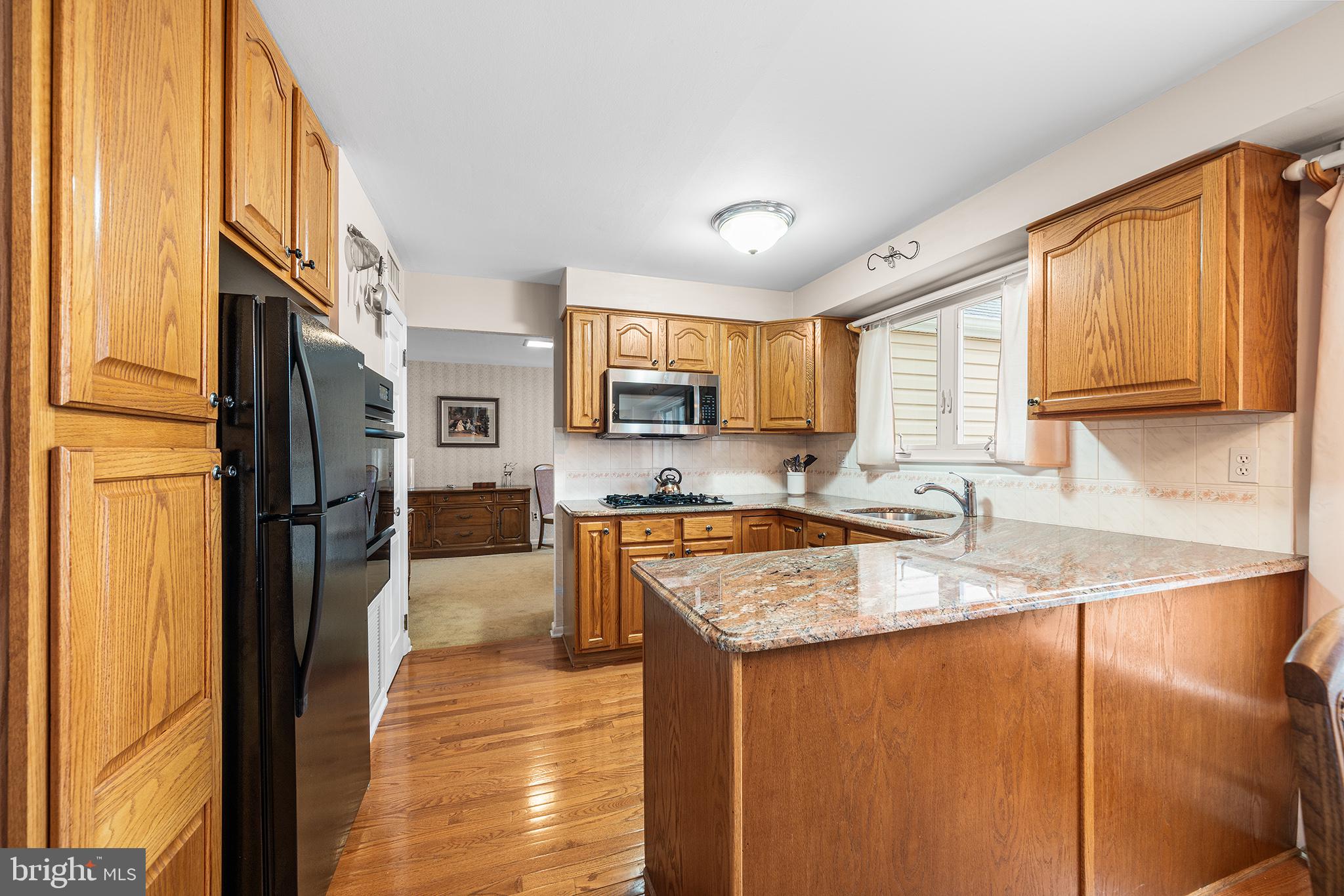 1571 Carousel Drive Warminster, PA 18974 - Photo 13 of 40 a kitchen with stainless steel appliances granite countertop a refrigerator a sink dishwasher a stove and white countertops with wooden floor