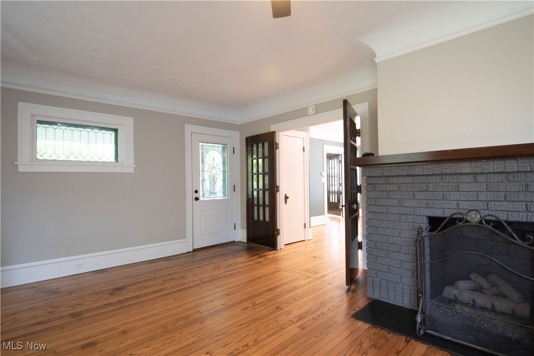 7003 Brecksville Road Independence, OH 44131 - Photo 8 of 35 Unfurnished living room featuring crown molding, wood finished floors, a fireplace, and ceiling fan