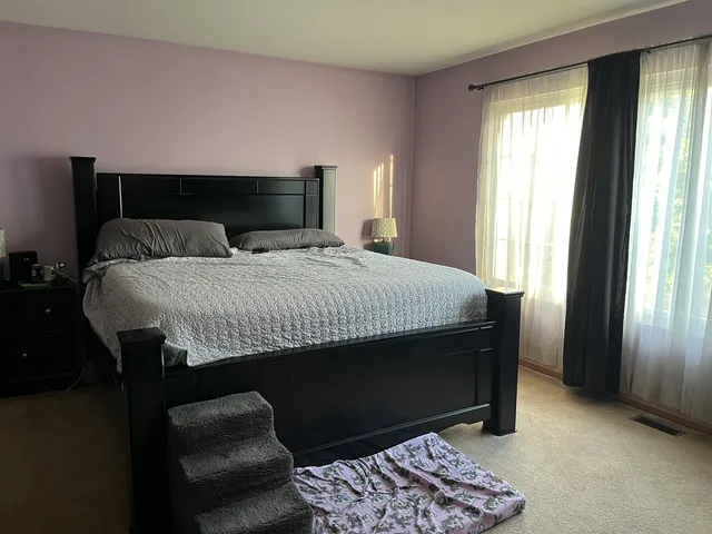 a bedroom with a bed and a dresser next to a window