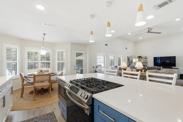 a kitchen with stainless steel appliances kitchen island granite countertop a dining table chairs and sink