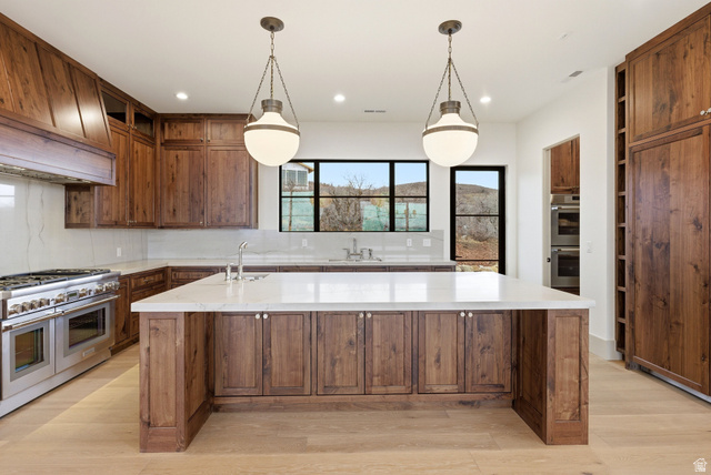 2155 East Wrangler Road Kamas, UT 84036 - Photo 36 of 62 Kitchen with a large island with sink, stainless steel appliances, backsplash, light stone countertops, and light wood-style flooring