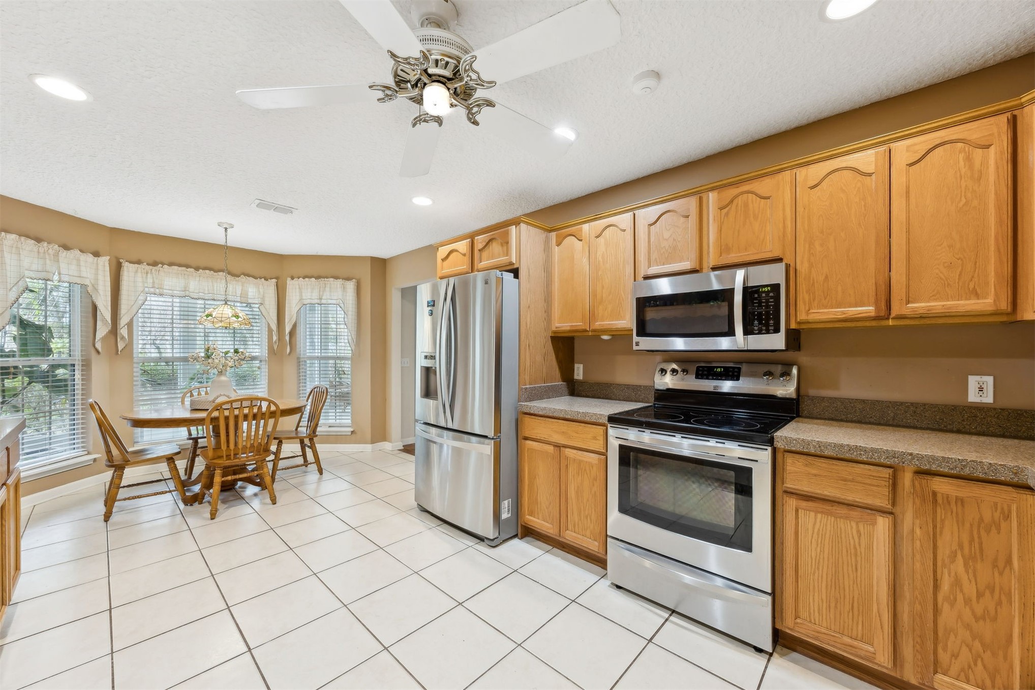 86341 Meadowfield Bluffs Road Yulee, FL 32097 - Photo 18 of 68 a kitchen with stainless steel appliances granite countertop a stove top oven a sink dishwasher a dining table and chairs with wooden floor