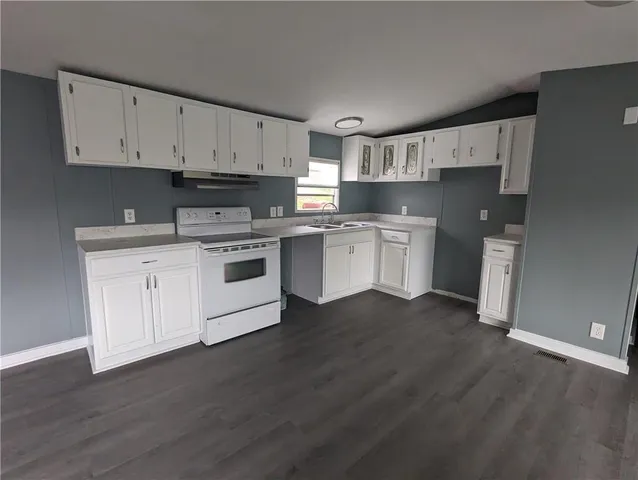 a kitchen with stainless steel appliances white cabinets and wooden floor