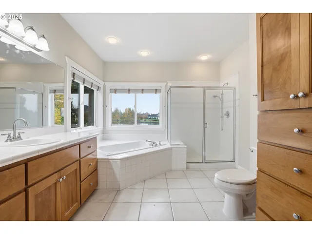 a bathroom with a granite countertop sink a toilet mirror and bathtub