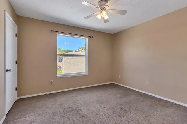 an empty room with a window and a fan