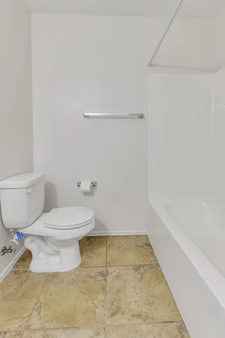 a white toilet sitting next to a bath tub