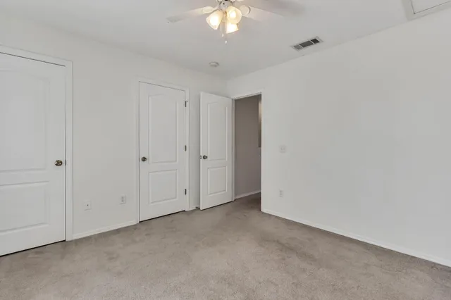 a view of an empty room and a chandelier fan