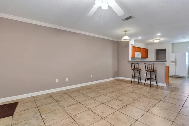 an empty room with chandelier fan and windows