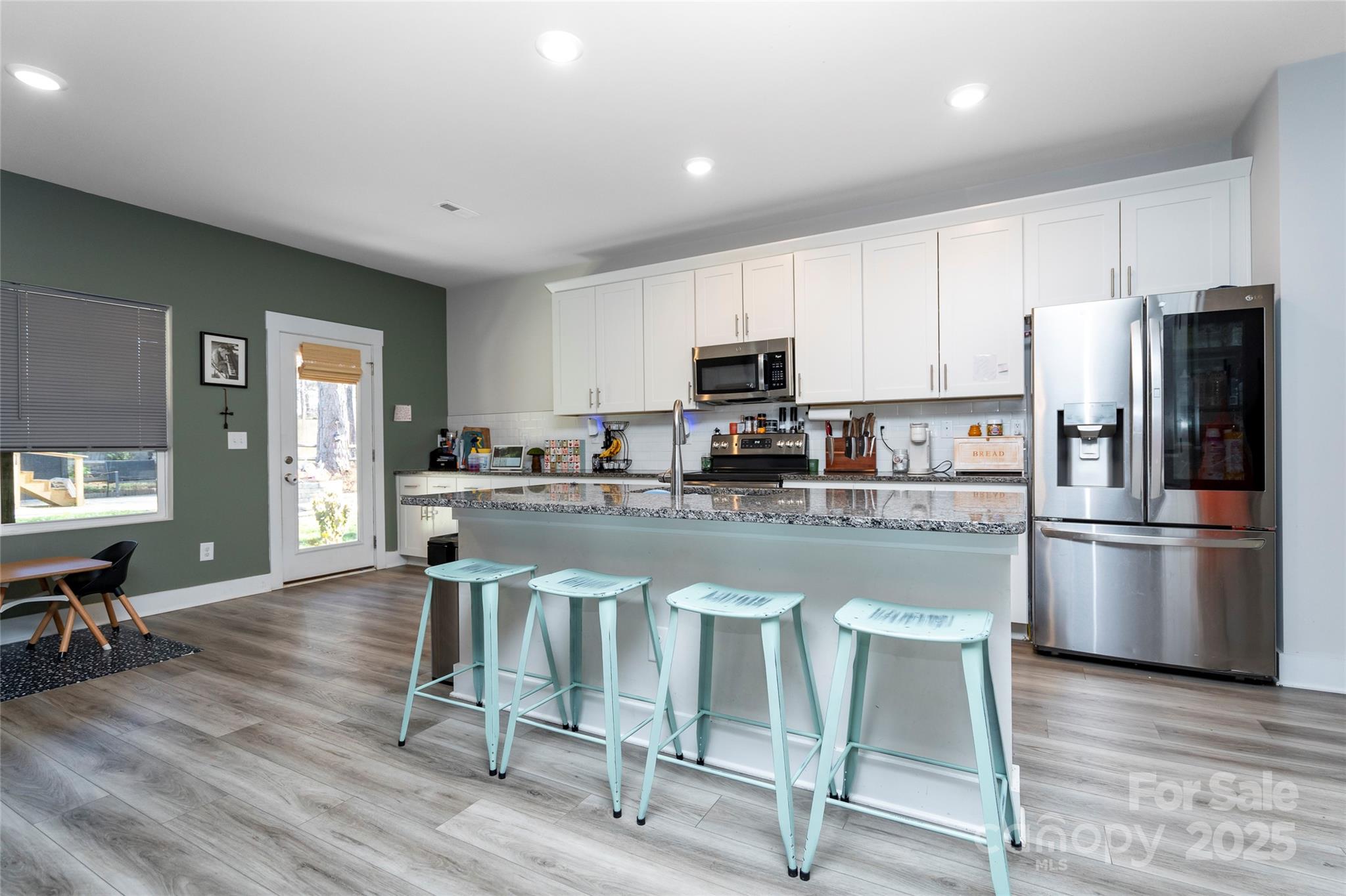 17359 Huntersville-Concord Road Huntersville, NC 28078 - Photo 8 of 41 a kitchen with stainless steel appliances granite countertop a stove a refrigerator a microwave a sink and white cabinets with wooden floor