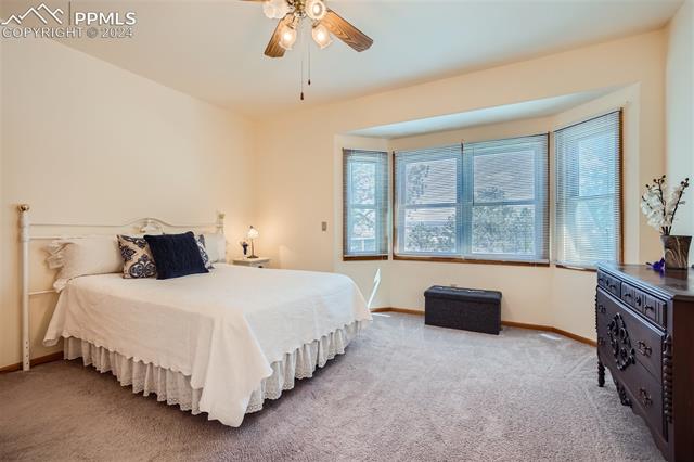 3715 Range View Road Monument, CO 80132 - Photo 17 of 49 Bedroom with light colored carpet, bay window looking out to the privet backyard and ceiling fan.