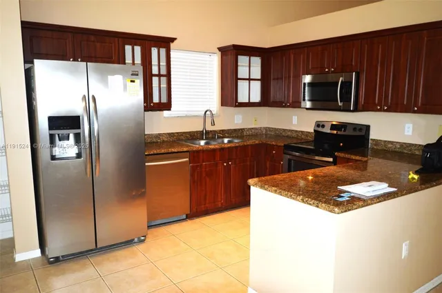 a kitchen with granite countertop stainless steel appliances a refrigerator and a sink