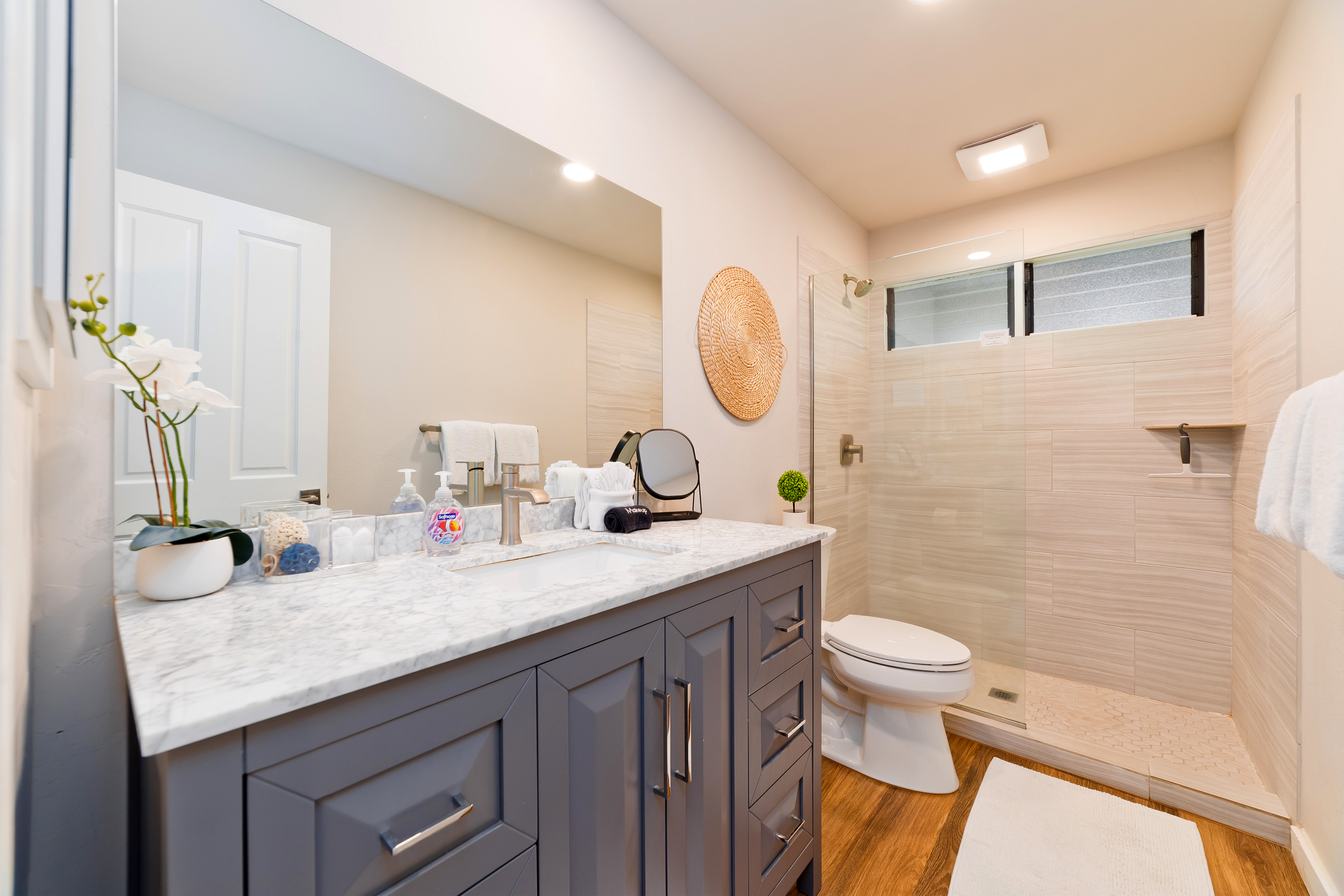 78-261 Manukai Street, Unit 303 Kailua-Kona, HI 96740 - Photo 19 of 30 a bathroom with a granite countertop sink a toilet and a mirror