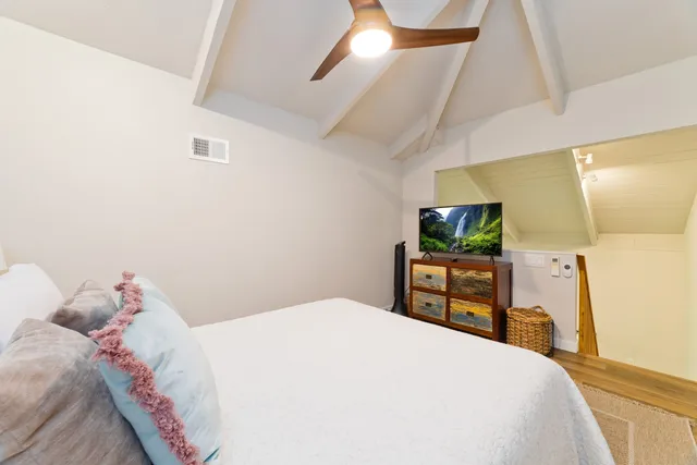 a bedroom with a bed and a flat tv screen on dresser
