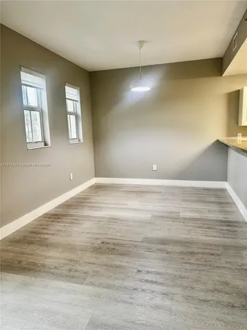 a view of empty room with window and wooden floor