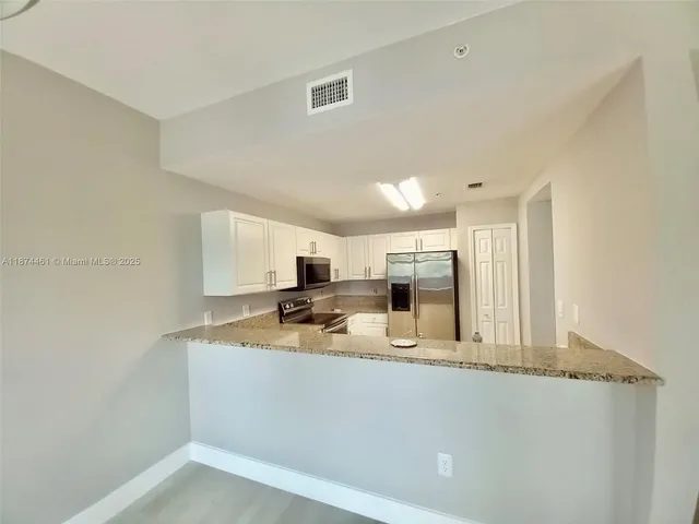 a kitchen with stainless steel appliances granite countertop a sink refrigerator and cabinets