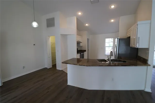 a kitchen with kitchen island granite countertop a sink and a refrigerator