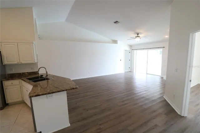 a kitchen with granite countertop a sink cabinets and wooden floor